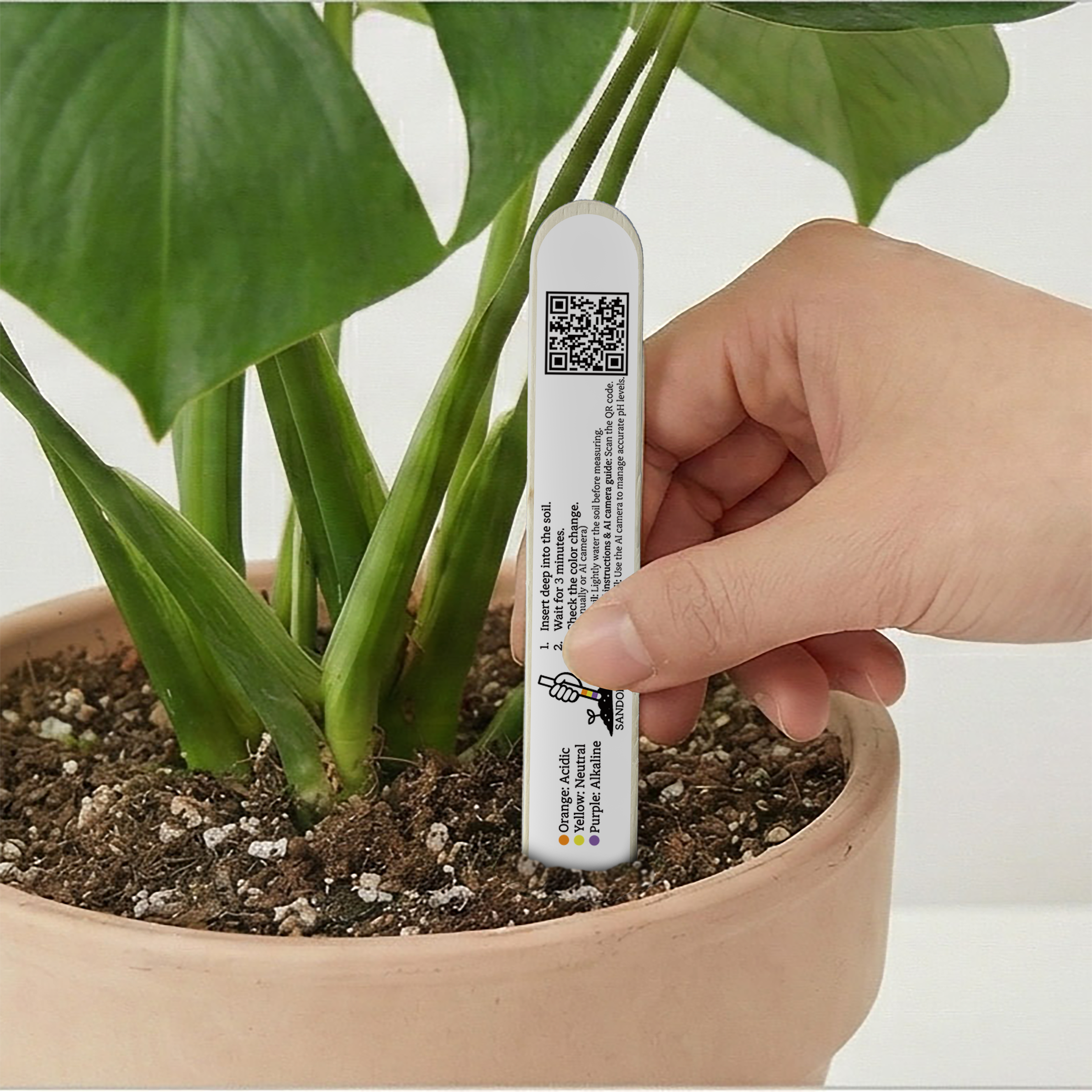 A SANDOBARO PLUS stick being inserted into a plant pot